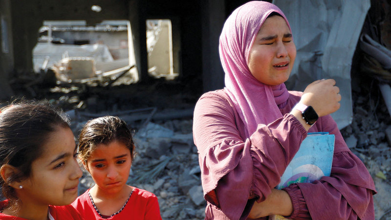 فتيات يبكين أمام منزلهن المنهار في دير البلح وسط غزة. رويترز