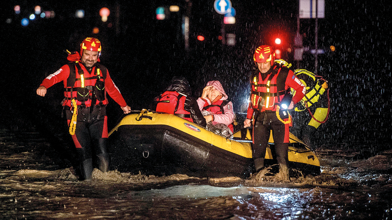 رجال الإطفاء ينقذون امرأة تعرض منزلها للغرق.   أ.ف.ب