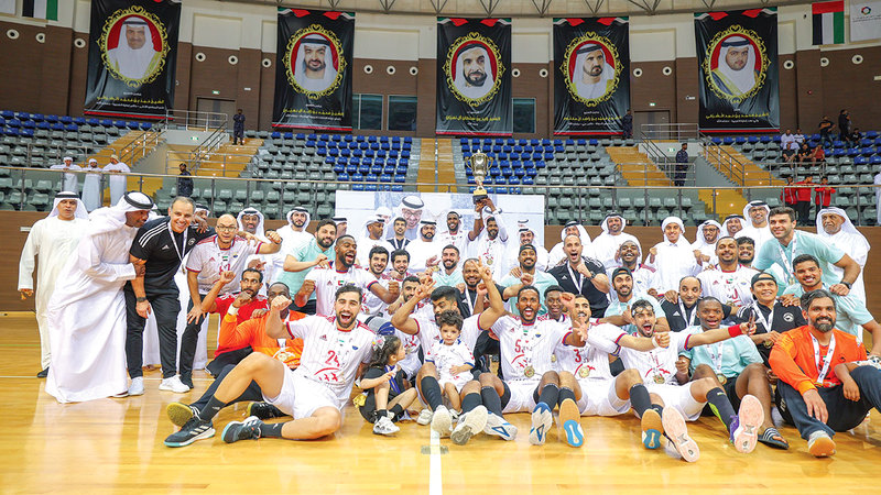 محمد بن حمد الشرقي يتوسط فريق الشارقة بطل كأس اليد. من المصدر