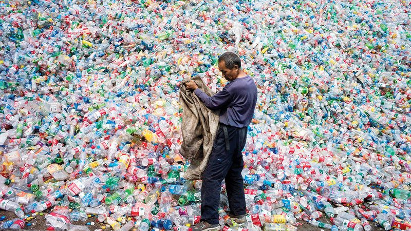 رجل داخل مكب عبوات بلاستيكية في بكين.     أ.ف.ب