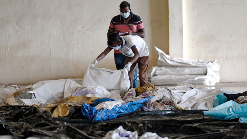 أفراد يحاولون التعرف على ذويهم من بين الجثث.   أ.ف.ب