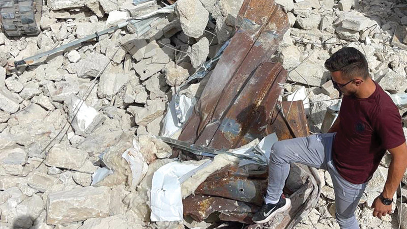 الشاب إبراهيم أبوطير يقف فوق ركام منزله.   الإمارات اليوم