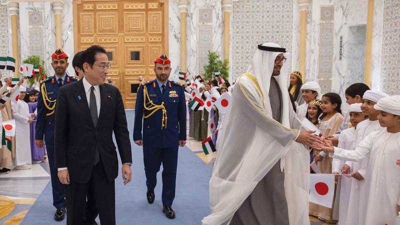 محمد بن زايد يصافح مجموعة من الأطفال شاركوا في استقبال رئيس وزراء اليابان.  وام