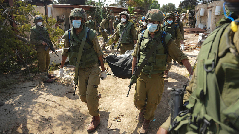 جنود إسرائيليون يحملون جثة أحد قتلى هجمات «حماس». أ.ب