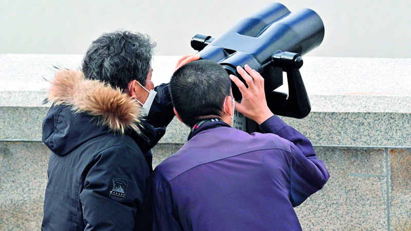 زوار وسياح يراقبون بالمنظار الأماكن البعيدة. أ.ف.ب