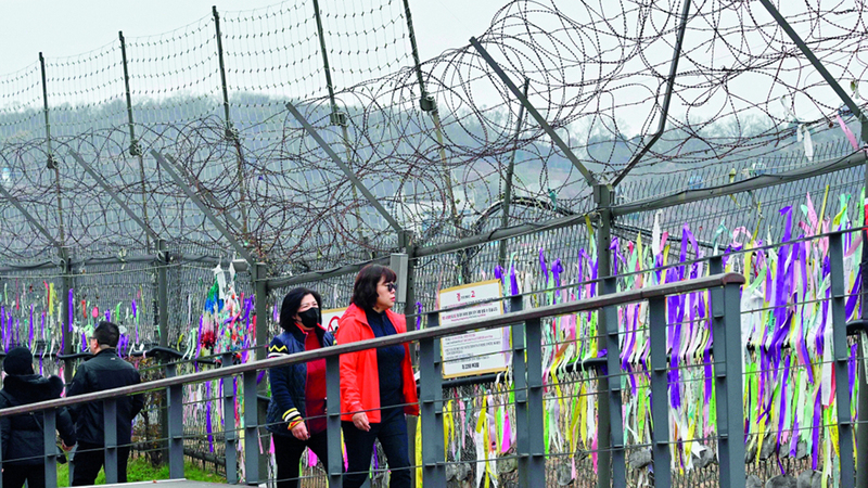 زوار يسيرون بجانب سياج العزل. أ.ف.ب