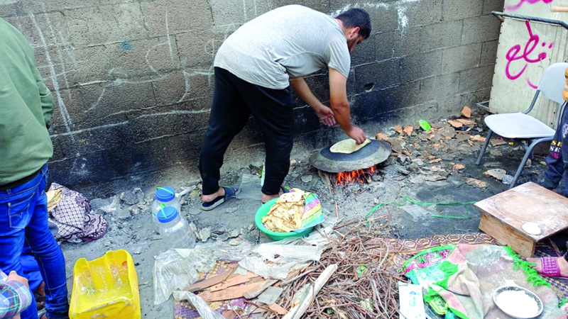 غزيون يخبزون العجين على الصاج ليصبح صالحاً للأكل. الإمارات اليوم