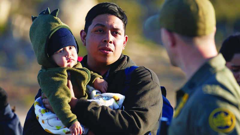 مهاجر مع  ابنه أثناء معاملة الهجرة على الحدود الأميركية. إي.بي.إيه