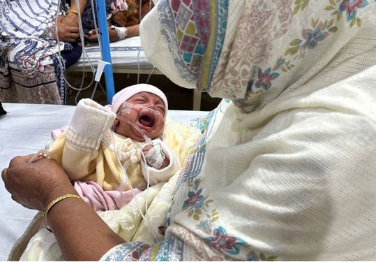 طفلة تبلغ من العمر شهراً واحداً، نور تبكي بينما تريحها جدتها داخل جناح الأطفال في مستشفى سير جانجا رام حيث تعالج من الالتهاب الرئوي وسط ارتفاع تلوث الهواء في لاهور، باكستان