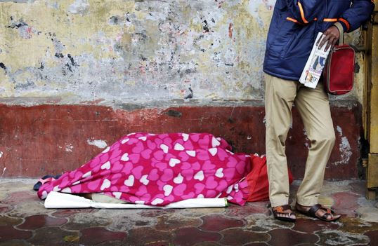 شخص ملقى في الشارع يستخدم بطانية لحماية نفسه من البرد أثناء هطول الأمطار في كولكاتا، في أعقاب إعصار ميتشونج، الهند - الصور عن وكالات