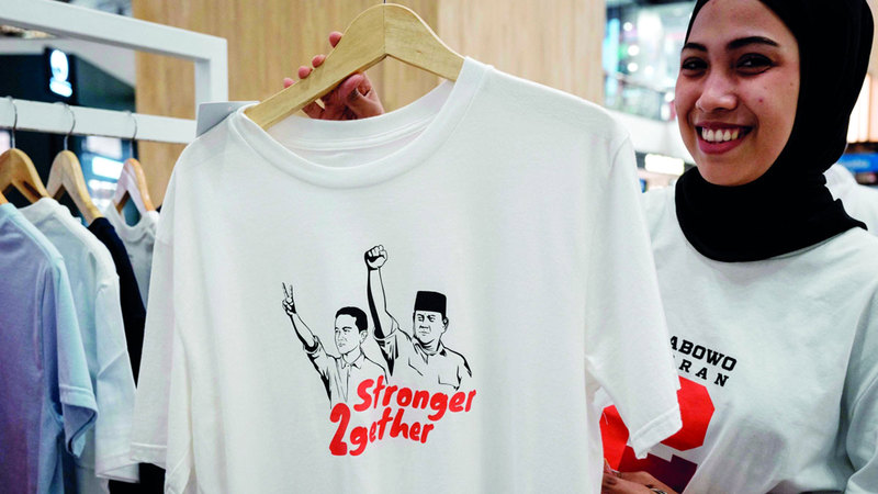 فتاة تعرض قميصاً عليه صور مرشحين. أرشيفية