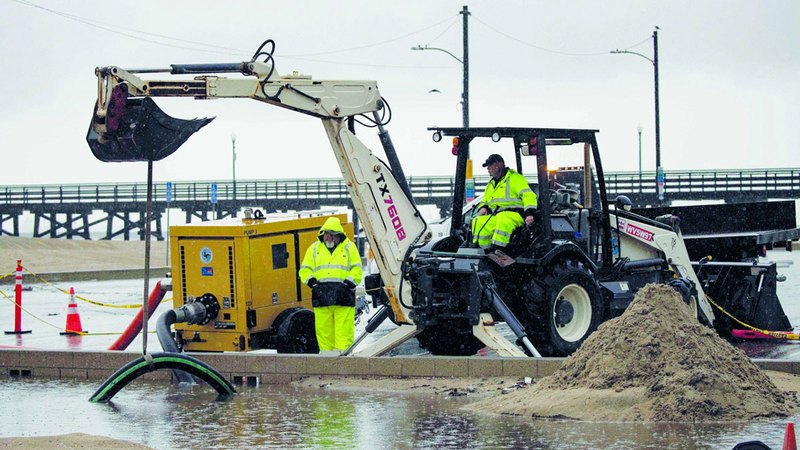 عمال يحاولون محاصرة السيول. إي.بي.إيه
