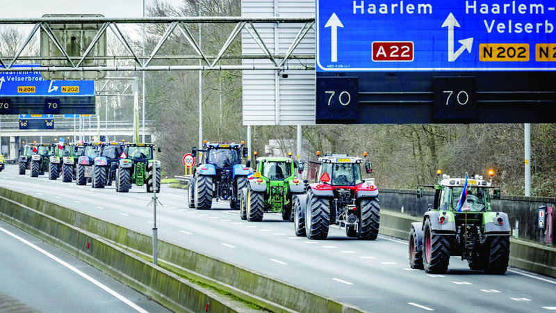 مزارعون يقودون جراراتهم في مسيرة احتجاجية على طول الطريق السريع.   إي.بي.أيه