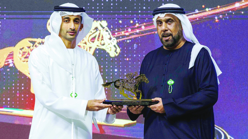 راشد بن دلموك يسلم جائزة العطاء الدؤوب لعبدالله بن ماجد القاسمي. من المصدر