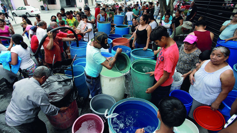 سكان ينتظرون مجيء الصهريج لملء بعض الأوعية بالماء. أرشيفية