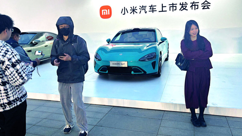 أشخاص يلتقطون صوراً أمام أول سيارة كهربائية من طراز «أس يو 7 أكسياومي» خلال إطلاقها في بكين. رويترز