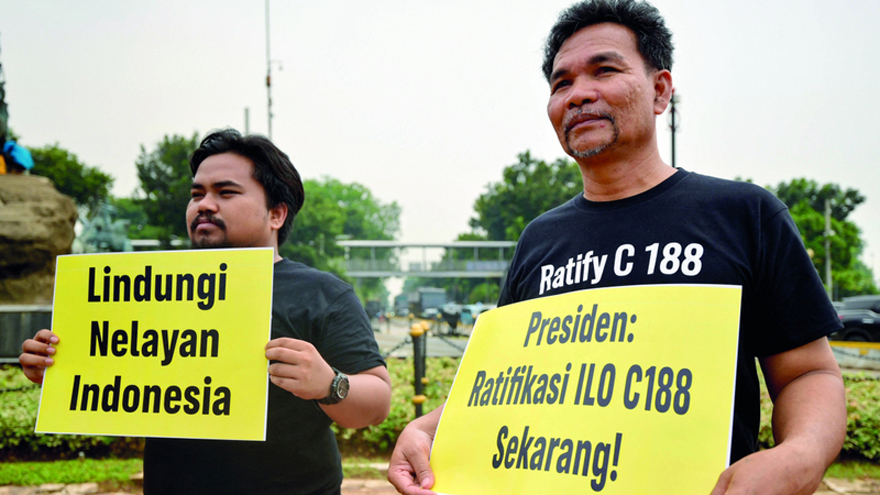 ناشطان يحملان لافتات تطالب بالتصديق على اتفاقية العمل الدولية. أ.ف.ب    