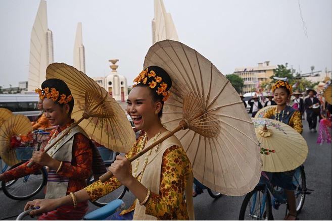فنانون يرتدون الزي التايلاندي التقليدي يسيرون أمام القصر الكبير خلال موكب للاحتفال بالعام التايلاندي الجديد القادم، والمعروف محليًا باسم سونغكران، في بانكوك. الصور عن AFP