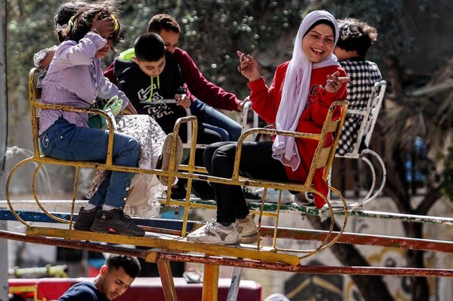 أطفال يجلسون على أرجوحة وهم يحتفلون في اليوم الأول من عطلة عيد الفطر، بعد انتهاء شهر رمضان المبارك، في دير البلح وسط قطاع غزة ، الصور عن وكالات