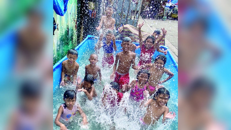 صبية في العاصمة الفلبينية مانيلا يسبحون في بركة اصطناعية بالقرب من أحد الشوارع. إي.بي.إيه
