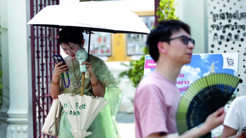 نساء في العاصمة التايلاندية بانكوك يخففن حرارة الجو بمراوح يدوية. إي.بي.إيه