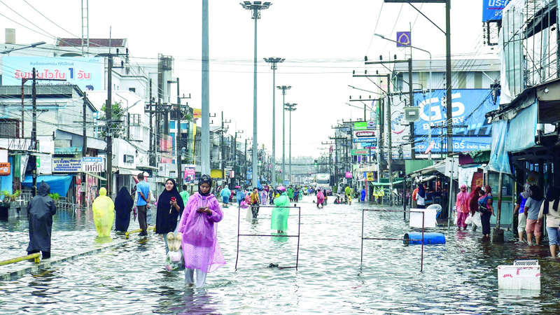 مشاة يقطعون شوارع مغمورة بمياه الأمطار. أ.ف.ب