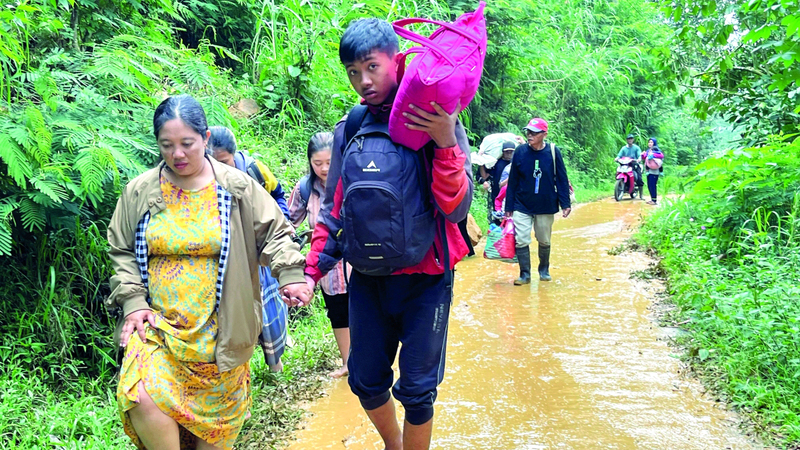 أشخاص يسيرون على طريق موحل في بيكالونجان. أ.ب