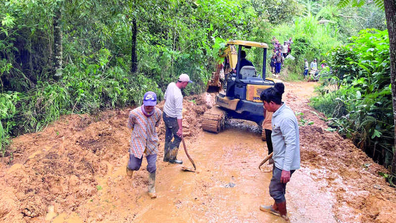 عمال ينظفون طريقاً قُطع بسبب انهيار أرضي في أعقاب فيضان مفاجئ. أ.ب