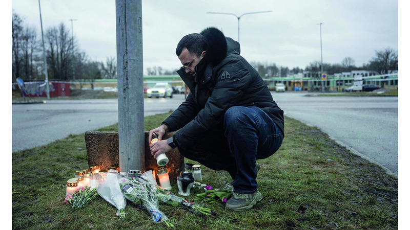 رجل يضع شمعة في مكان الحادث. أ.ب