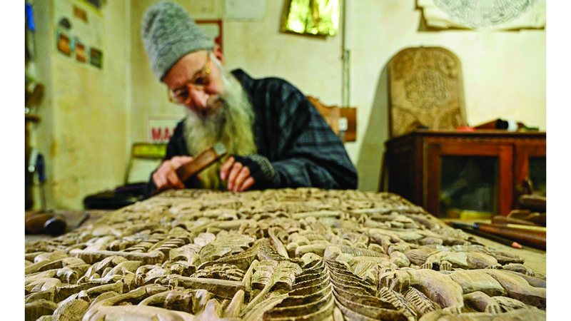 Wood carving artisan Ghulam Nabi Dar crafts designs on a wooden piece, at his workshop in Srinagar on February 18, 2025. (Photo by Tauseef MUSTAFA / AFP)