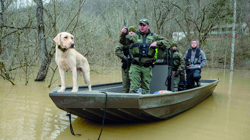 فريق إنقاذ مع كلبهم على متن قارب في إحدى المناطق المتضررة. أ ف ب