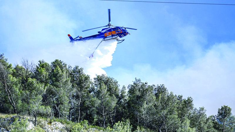 مروحية تسقط الماء من الجو للمساعدة في السيطرة على النيران. إي.بي.إيه