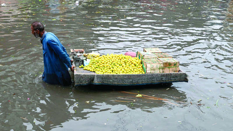 بائع يسحب بضاعته في طريق غمرته المياه. أ.ف.ب