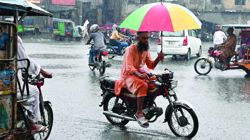 سكان يتنقلون وسط مدينة لاهور خلال تساقط الأمطار الغزيرة. أ.ف.ب