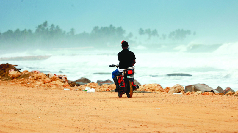 رجل على دراجته النارية يراقب الأمواج. رويترز