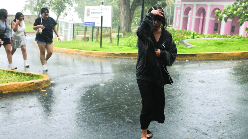 مارّة في شارع سان خوان بجزيرة «بورتوريكو» خلال العاصفة. إي.بي.إيه