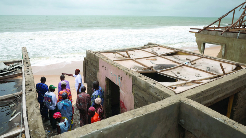 سكان يتفقدون منازل تضررت بسبب أمواج المحيط. رويترز