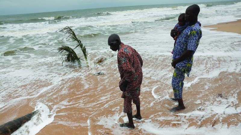 شخصان يقفان في موقع منزلهما قبل أن تجرفه أمواج المحيط. رويترز