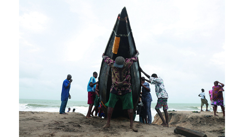 صيادون يحاولون إبعاد قاربهم عن الشاطئ. رويترز