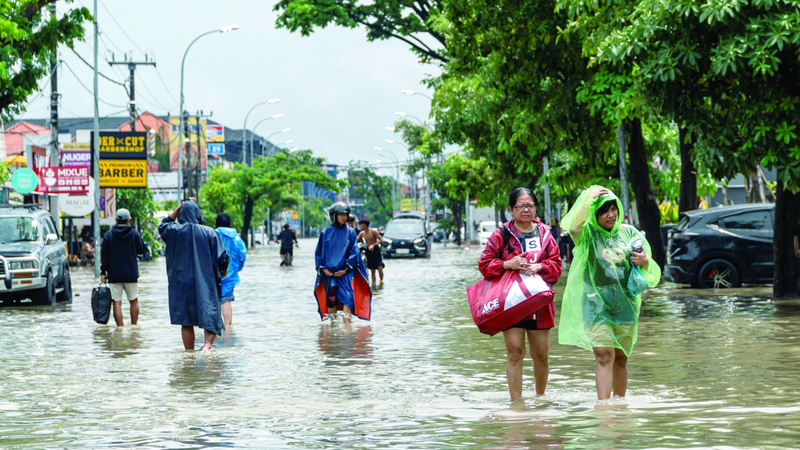 سكان يحملون أمتعتهم في شارع غمرته مياه الفيضانات. رويترز