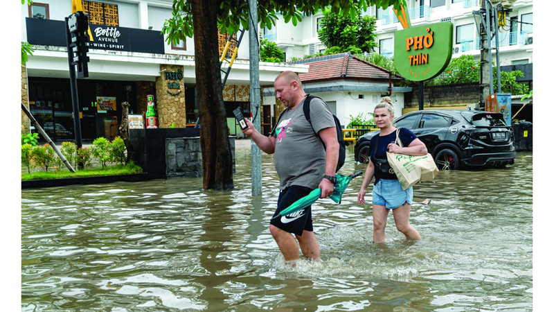 سائحان أجنبيان يعبران أحد طرق بالي التي غمرتها مياه الفيضانات. رويترز