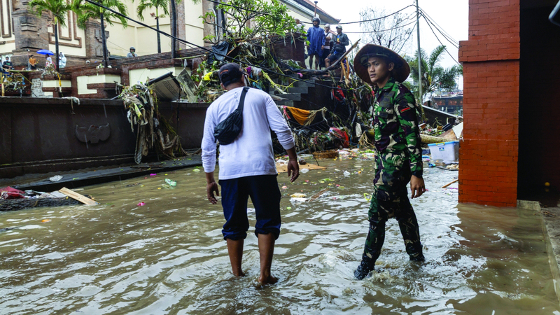 شخصان يشقان طريقهما في مياه الفيضانات بسوق تقليدية. إي.بي.إيه