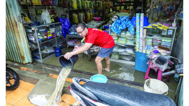 رجل ينظّف متجره من مخلفات السيول.  إي.بي.إيه