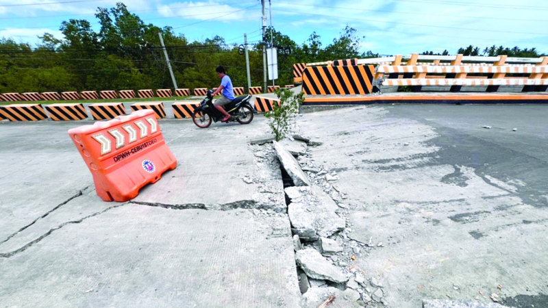 شاب يعبر جسراً متضرراً في أعقاب الزلزال بجزيرة سيبو. إي.بي.إيه