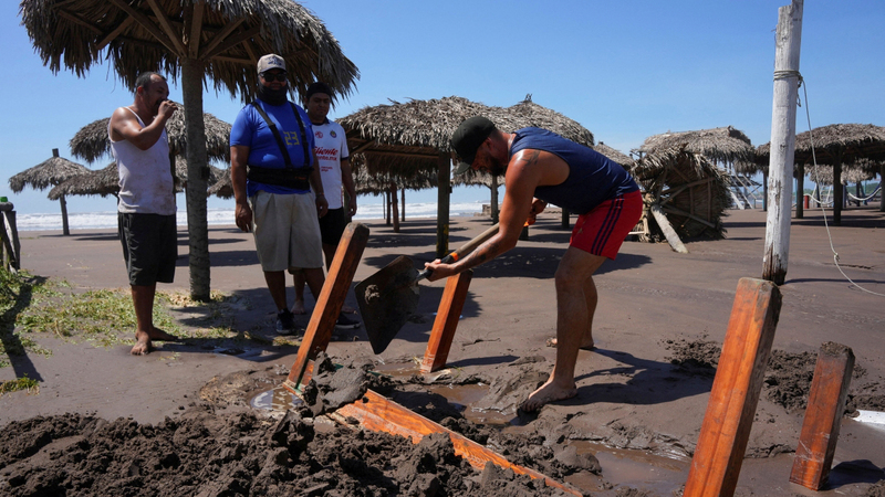 عمال يُزيلون الوحل من المحال المتضررة. رويترز