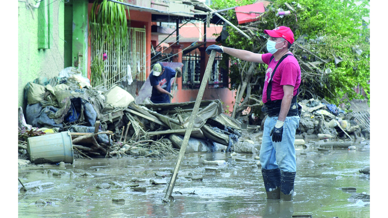 رجل ينظف الشارع بعد الفيضان المدمر. رويترز
