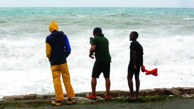أشخاص يراقبون الأمواج على شاطئ قريب من كينغستون. رويترز