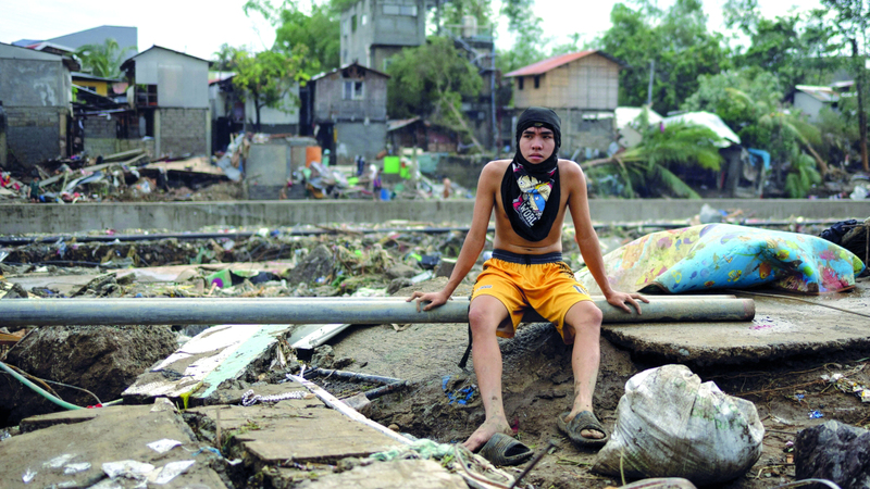 شاب يجلس على الأنقاض في منطقة ضربها الإعصار. رويترز