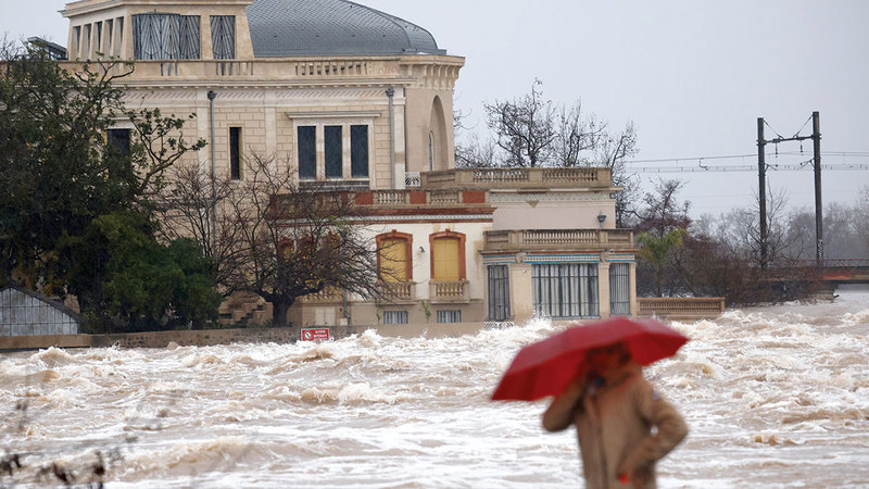 امرأة تسير بجوار نهر هيرولت بعد أن فاض بسبب الأمطار الغزيرة. إي.بي.إيه