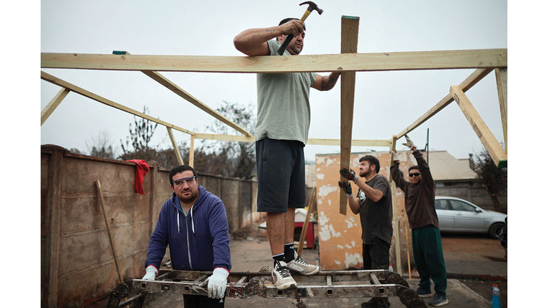أشخاص يعملون على بناء منزل بعد أن دمره الحريق. رويترز